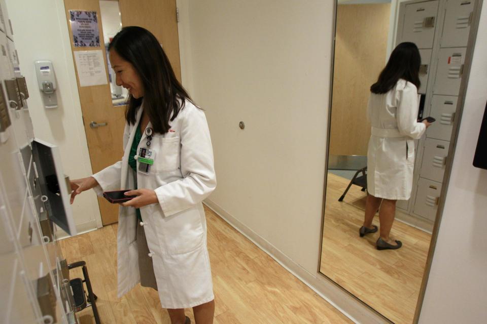 In this Tuesday, Aug. 14, 2012 photo Leana Wen, of Boston, who is doing her medical residency in emergency medicine at Harvard-affiliated Brigham and Women's Hospital and Massachusetts General Hospital,, deposits some personal belongings in a locker in the emergency department at Brigham and Women's Hospital, in Boston. Wen chose emergency medicine because the hours are more flexible than those of primary care physicians. (AP Photo/Steven Senne)