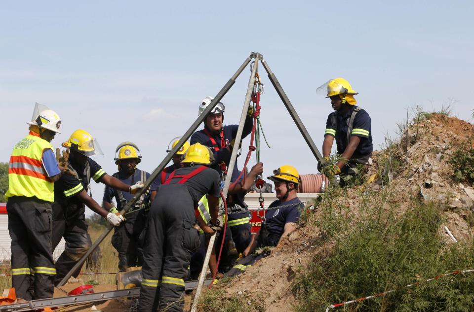 Rescue officials use hoists to remove debris as they work to rescue trapped suspected illegal miners from an abandoned gold shaft in Benoni