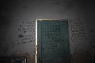 FILE - Writing covers a wall and a door in the basement of a school in Yahidne, near Chernihiv, Ukraine, Tuesday, April 12, 2022. Locals said more than 300 villagers were forced into the basement. Then, during weeks of stress and deprivation, some began to die. (AP Photo/Evgeniy Maloletka, File)