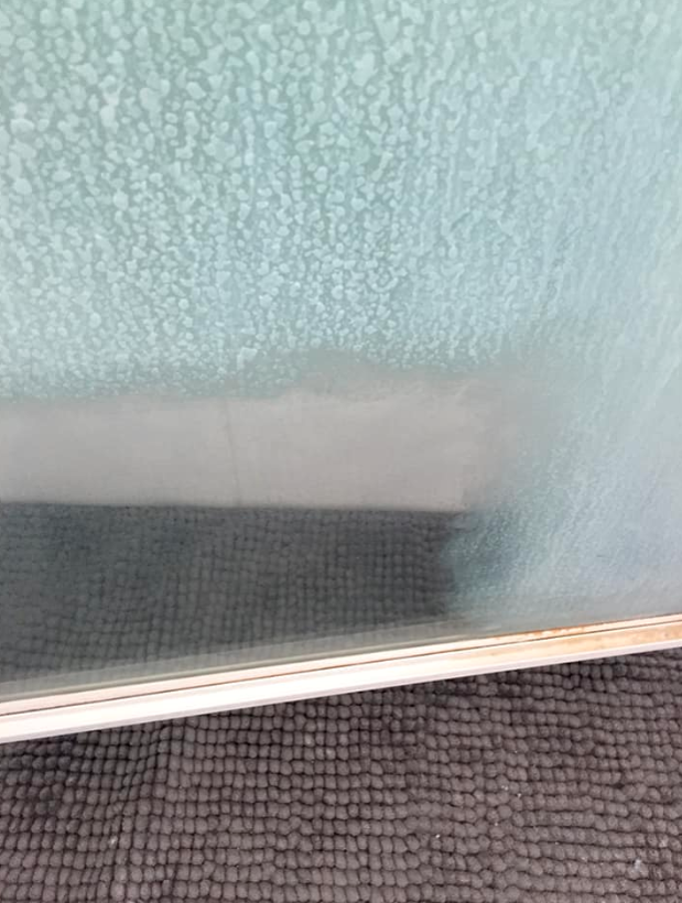 photo of a dirty shower screen tarnished with calcium build up 