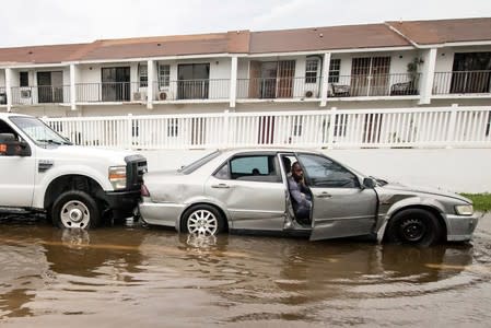 A man driving a stalled car is pushed through a flooded street after the effects of Hurricane Dorian arrived in Nassau