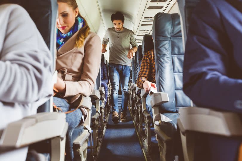 An image of a man striding down the centre aisle of a plane