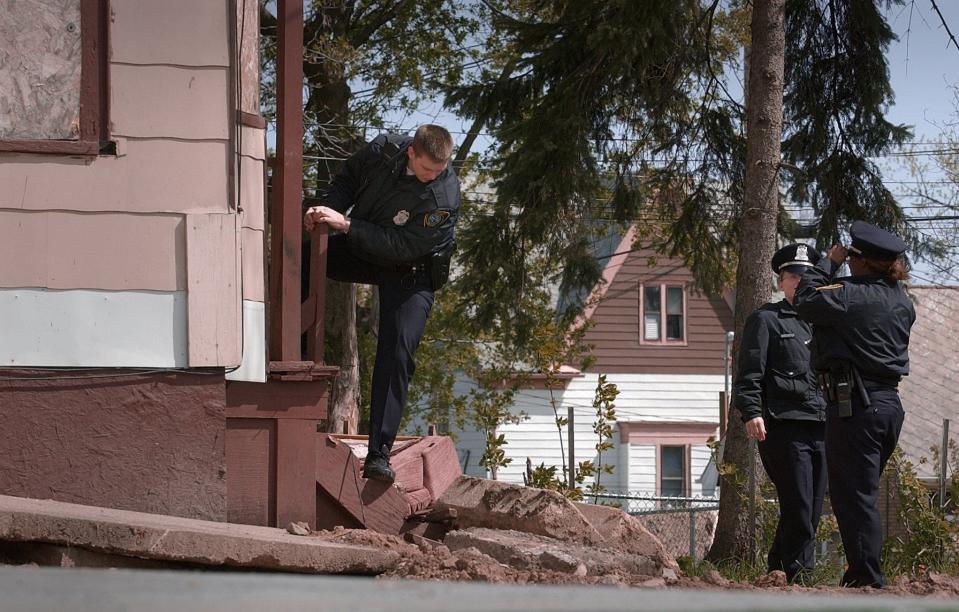 A Milwaukee Police officer climbs out of a boarded up home at 2106 N. 33rd St. while searching for Alexis Patterson Tuesday May 7, 2002. Patterson was last seen on May 3, 2002.