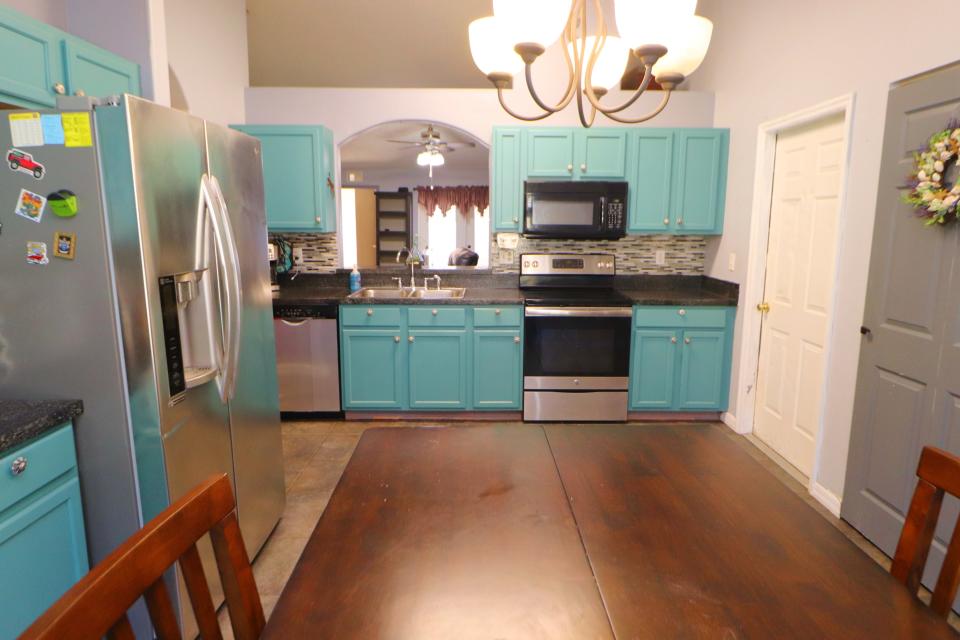 This updated kitchen has a lovely coastal feel, with its beach-blue cabinets, granite countertops, stainless-steel appliances and a large pass-through over the sink.