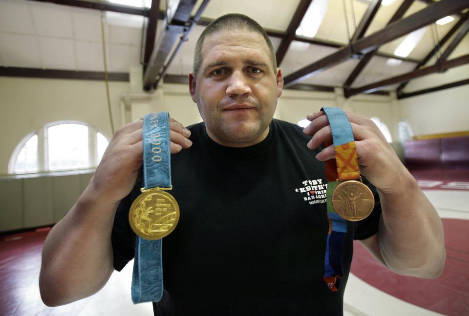 FILE - In this Feb. 27, 2007, file photo, Rulon Gardner holdslding his gold and his bronze Olympic medals after giving a motivational talk to students and faculty at the Middlesex School in Concord, Mass. In yet another setback for Gardner once lauded as the most decorated athlete in the history of American Greco-Roman wrestling, the Olympic gold medalist has filed for bankruptcy. (AP Photo/Michael Dwyer, File)