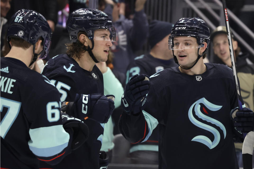 Seattle Kraken center John Hayden, second from left, is congratulated by center Morgan Geekie (67) and defenseman Will Borgen (3) after scoring against the Calgary Flames during the first period of an NHL hockey game Friday, Jan. 27, 2023, in Seattle. (AP Photo/John Froschauer)