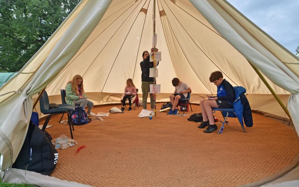 Teacher Holly Haime teaches year five pupils arts and crafts as they make paper aeroplanes inside a teepee style tent at Llanishen Fach Primary School in Cardiff - PA