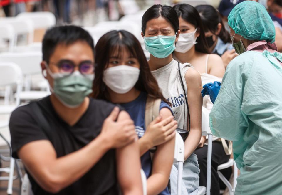 國內二十八日本土確診個案破萬，不少民眾前往北車接種站施打疫苗。（中央社）