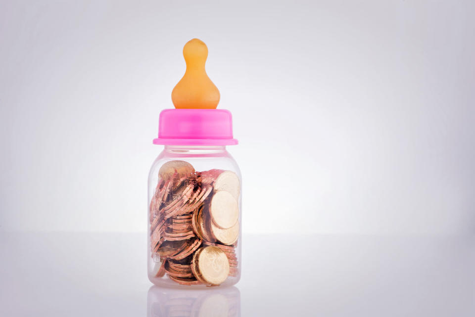 Baby Bottle Filled With Coins Against White Background