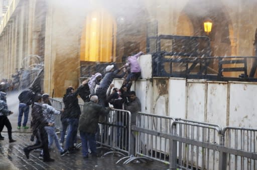 Lebanese protesters try to scale barricades blocking access to the parliament building in central Beirut as security forces spray them with water cannons