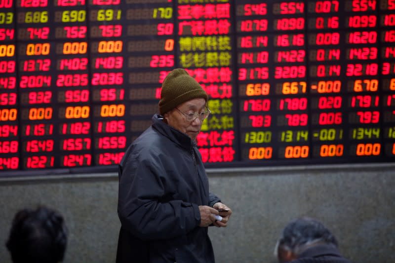 An investor walks in front of an electronic board showing stock information on the first trading day after the New Year holiday at a brokerage house in Shanghai, China, January 3, 2017. REUTERS/Aly Song