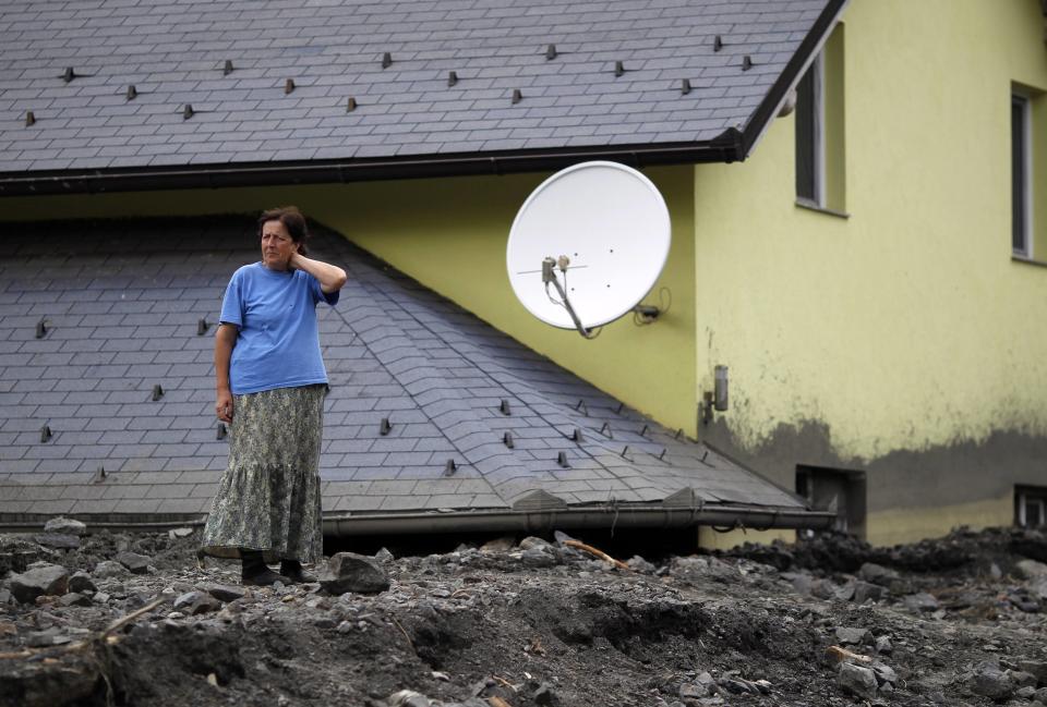 A woman stands in front of her flood-damaged house in Topcic Polje