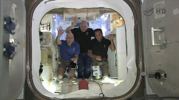 NASA astronauts Don Pettit (right) and Joe Acaba (left) with European Space Agency (ESA) astronaut Andre Kuipers wave from inside SpaceX’s Dragon spacecraft, now attached to the International Space Station
