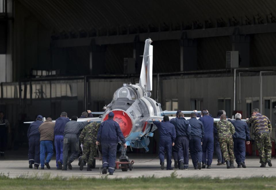 Romanian air force employees push a MIG 21 Lancer fighter jet in Campia Turzii, Romania, Thursday, April 10, 2014. Some 450 U.S. and Romanian troops are taking part in the Dacian Viper 2014 joint military exercise in Transylvania, northwestern Romania flying U.S. F-16 fighter jets of the U.S. 31st Fighter Wing alongside Romanian Mig-21 Lancers.The weeklong exercise, the fourth of its kind, was planned before Russia’s recent annexation of Crimea, according to officials.(AP Photo/Vadim Ghirda)