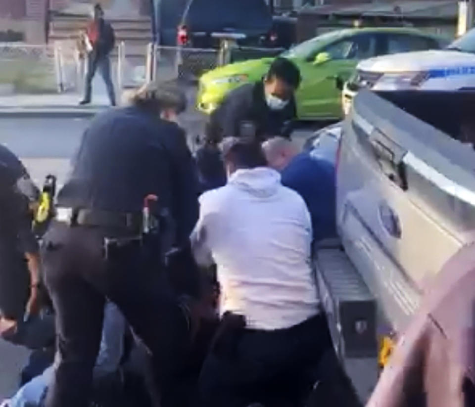 In this April 29, 2020 image made from video provided by Adegoke Atunbi, New York City police officers wrestle a man to the ground while making an arrest in the Brooklyn borough of New York. The video is among those posted on social media recently that show the NYPD using physical force while out enforcing the city's 6-foot-of-distance social distance rule. Despite mounting pressure from watchdogs to stop using police to enforce social distancing, Mayor Bill de Blasio stood by the practice on Thursday, May 7, saying: "We're not going to sideline the NYPD." (Adegoke Atunbi via AP)