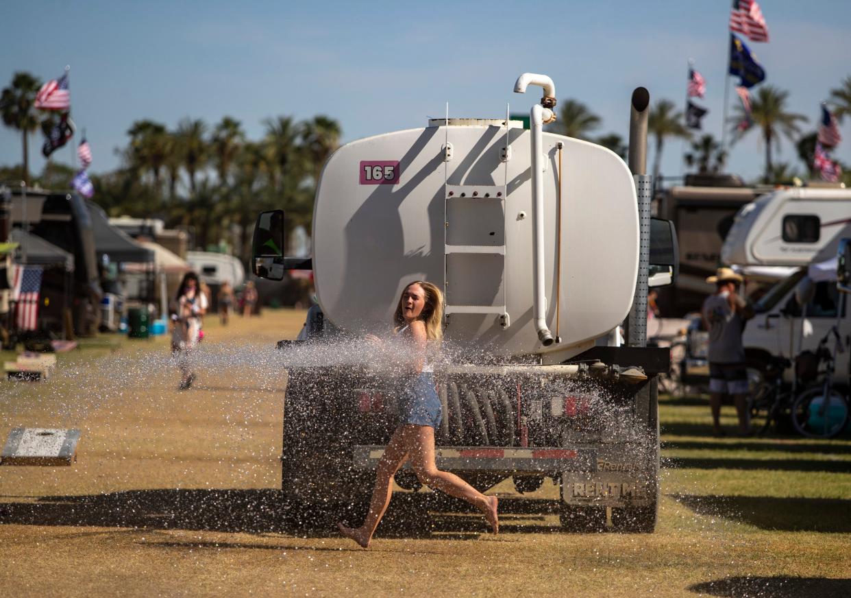 A festivalgoer runs out into the spray of a water truck used to keep the dust down in The Resort camping area at Stagecoach at the Empire Polo Club in Indio last April. Temperatures are expected to again reach triple digits during the PowerTrip heavy metal festival at the Empire Polo Club this weekend.