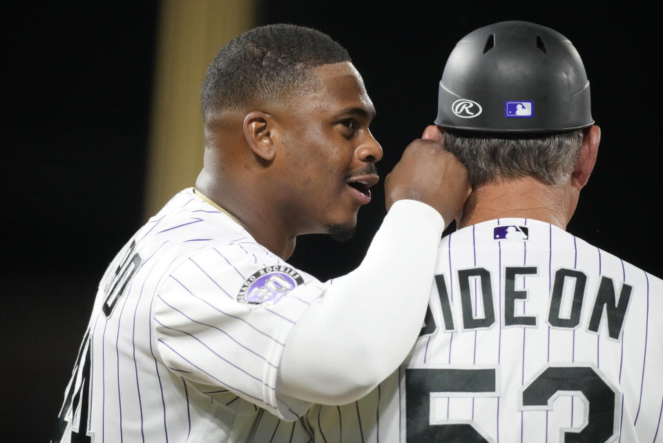 Colorado Rockies' Elehuris Montero, left, talks to first base coach Ronnie Gideon as they wait during a pitching change by the Oakland Athletics in the eighth inning of a baseball game Friday, July 28, 2023, in Denver. (AP Photo/David Zalubowski)