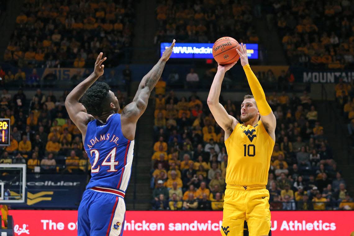 West Virginia guard Erik Stevenson (10) is defended by Kansas forward K.J. Adams Jr. (24) during the second half of an NCAA college basketball game in Morgantown, W.Va., Saturday, Jan. 7, 2023. (AP Photo/Kathleen Batten)