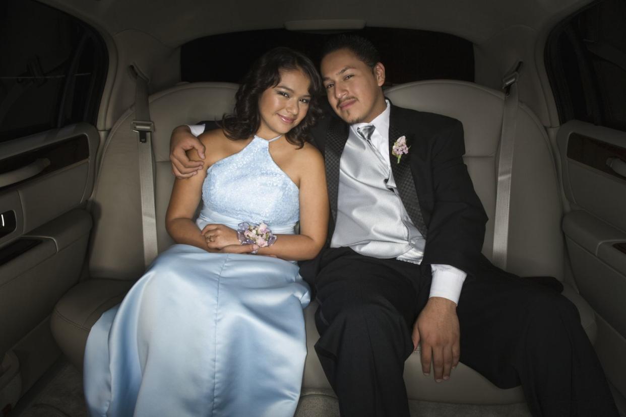 hispanic teenaged couple hugging in limousine