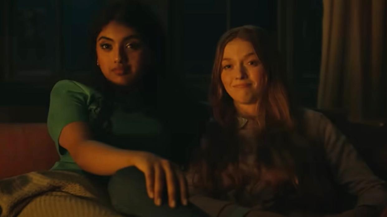  Avantika and Larsen Thompson's characters sit next to each other in a candlelit room in a scene from the movie Tarot. 