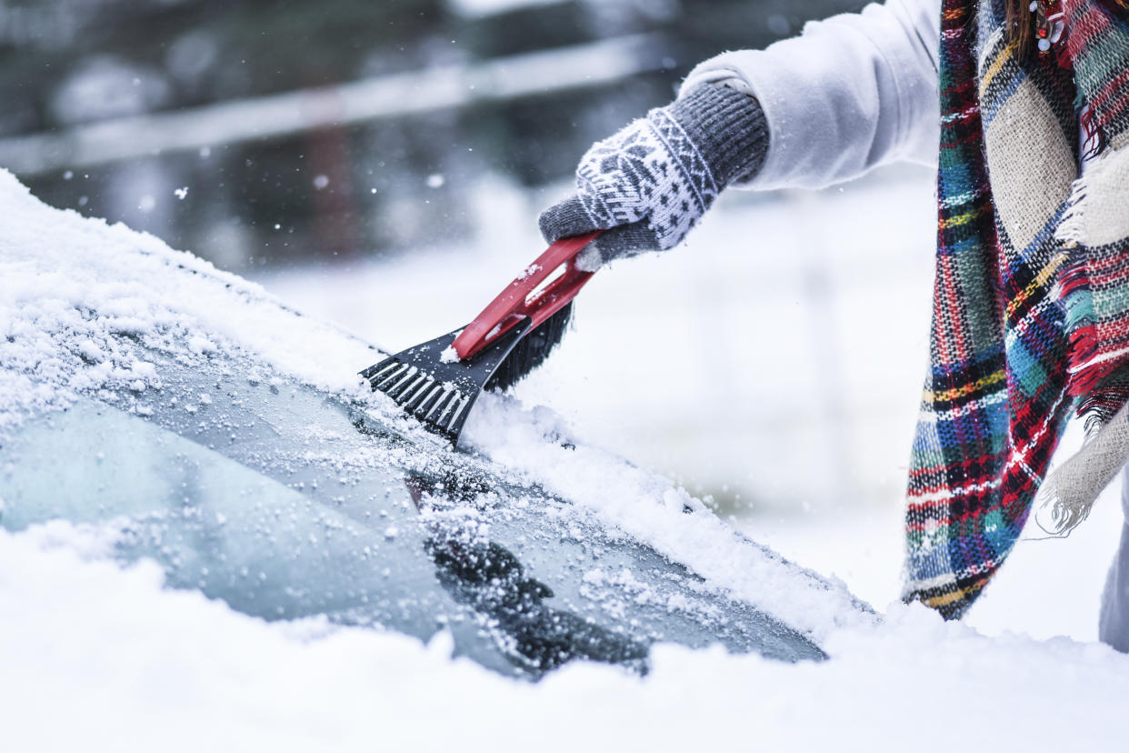 Woman cleaning snow from windshield,