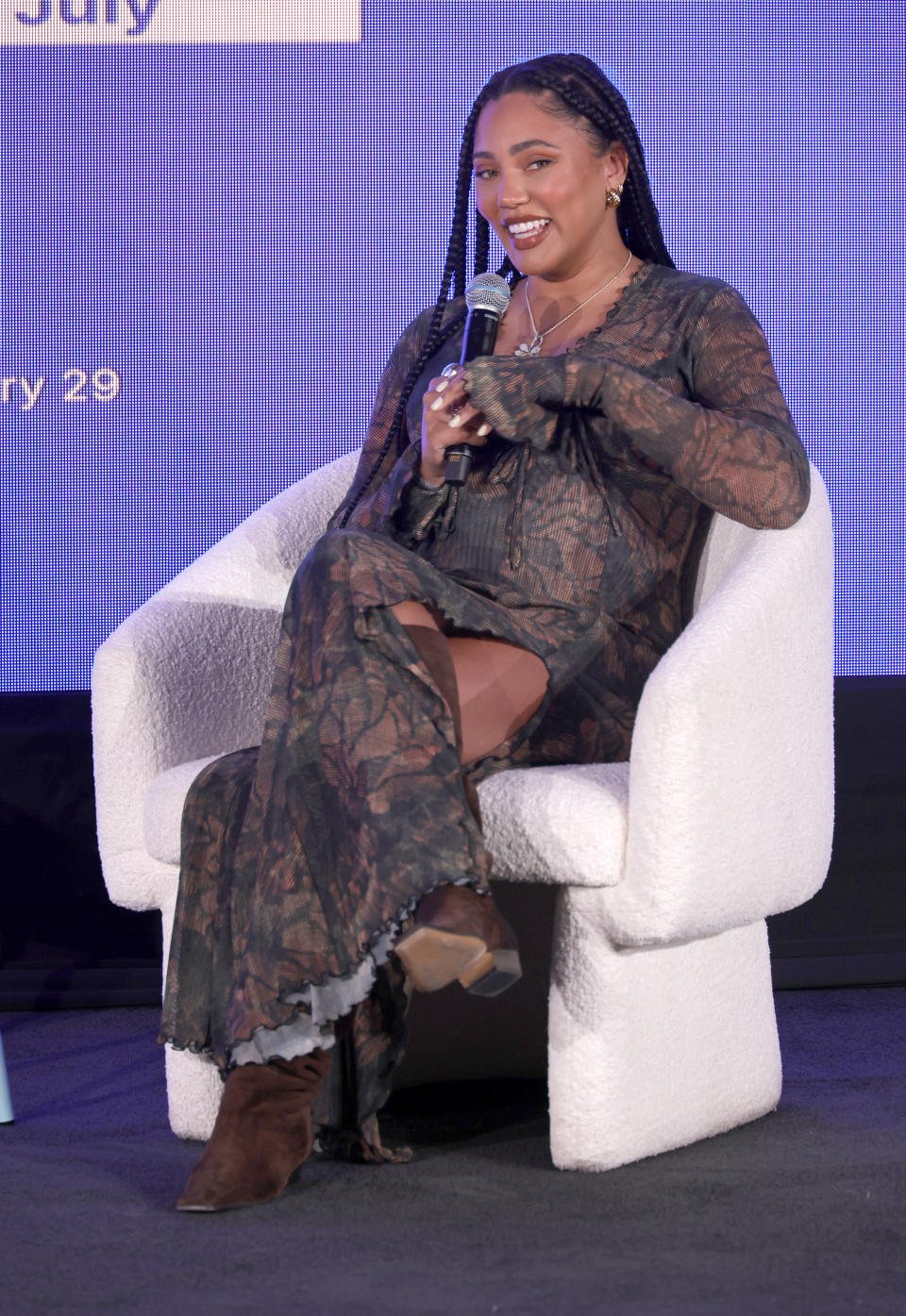 Ayesha Curry, speaks on stage during a Fireside chat in brown mid-calf boots