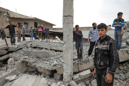 Displaced Iraqi men stand on remains of a destroyed building as the battle between the Iraqi Counter Terrorism Service and Islamic State militants continues nearby, in western Mosul, Iraq, April 23, 2017. REUTERS/Marko Djurica