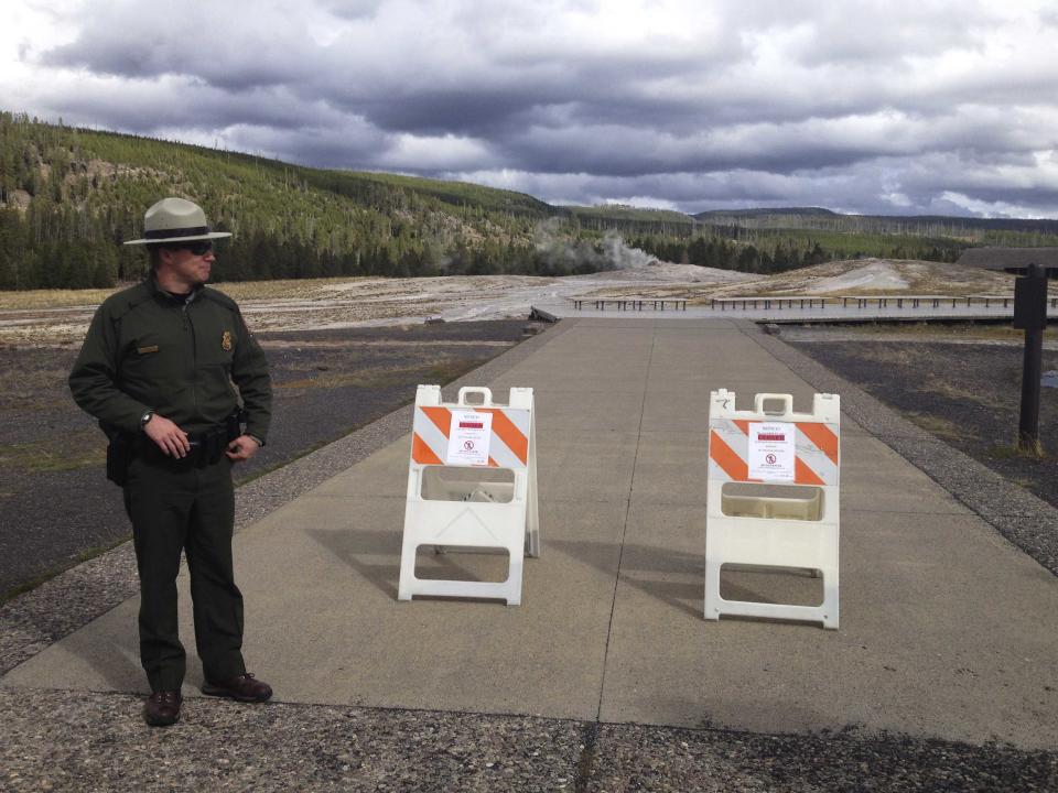 A park ranger next to a sign announcing the closure of the Old Faithful Geyser is pictured at Yellowstone National Park in Wyoming October 1, 2013 in the wake of the government shutdown. U.S. President Barack Obama scaled back a long-planned trip to Asia on October 2, 2013 and planned a meeting with Democratic and Republican leaders in Congress that both sides said was unlikely to yield an end to the government shutdown. Picture taken October 1, 2013. REUTERS/Christopher Cauble (UNITED STATES - Tags: POLITICS TRAVEL)