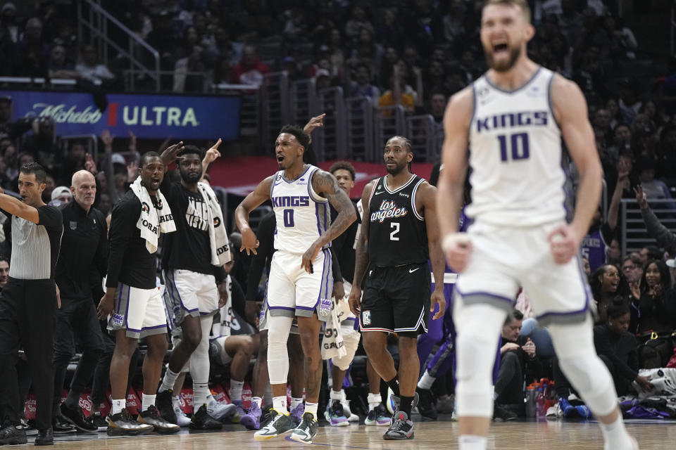 Sacramento Kings guard Malik Monk (0) celebrates along with forward Domantas Sabonis (10) after he scored as Los Angeles Clippers forward Kawhi Leonard walks between them during the first half of an NBA basketball game Friday, Feb. 24, 2023, in Los Angeles. (AP Photo/Mark J. Terrill)