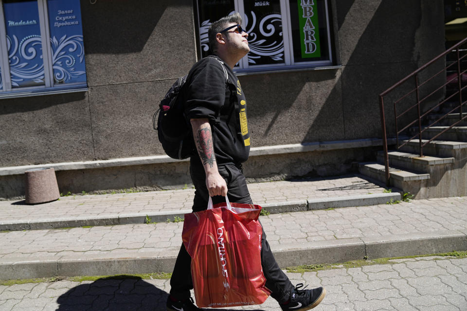 A Russian volunteer walks through Narva, Estonia, Thursday, June 16, 2022. The tattoo artist helps Ukrainians into Europe, making trips twice a week either to Finland or Estonia with them. (AP Photo)