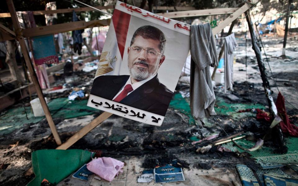 A photo taken on Aug 15, 2013 shows a portait of Mohamed Morsi, by then Egypt's ousted president, hanging admist debris at Rabaa al-Adawiya square in Cairo - MAHMOUD KHALED /AFP