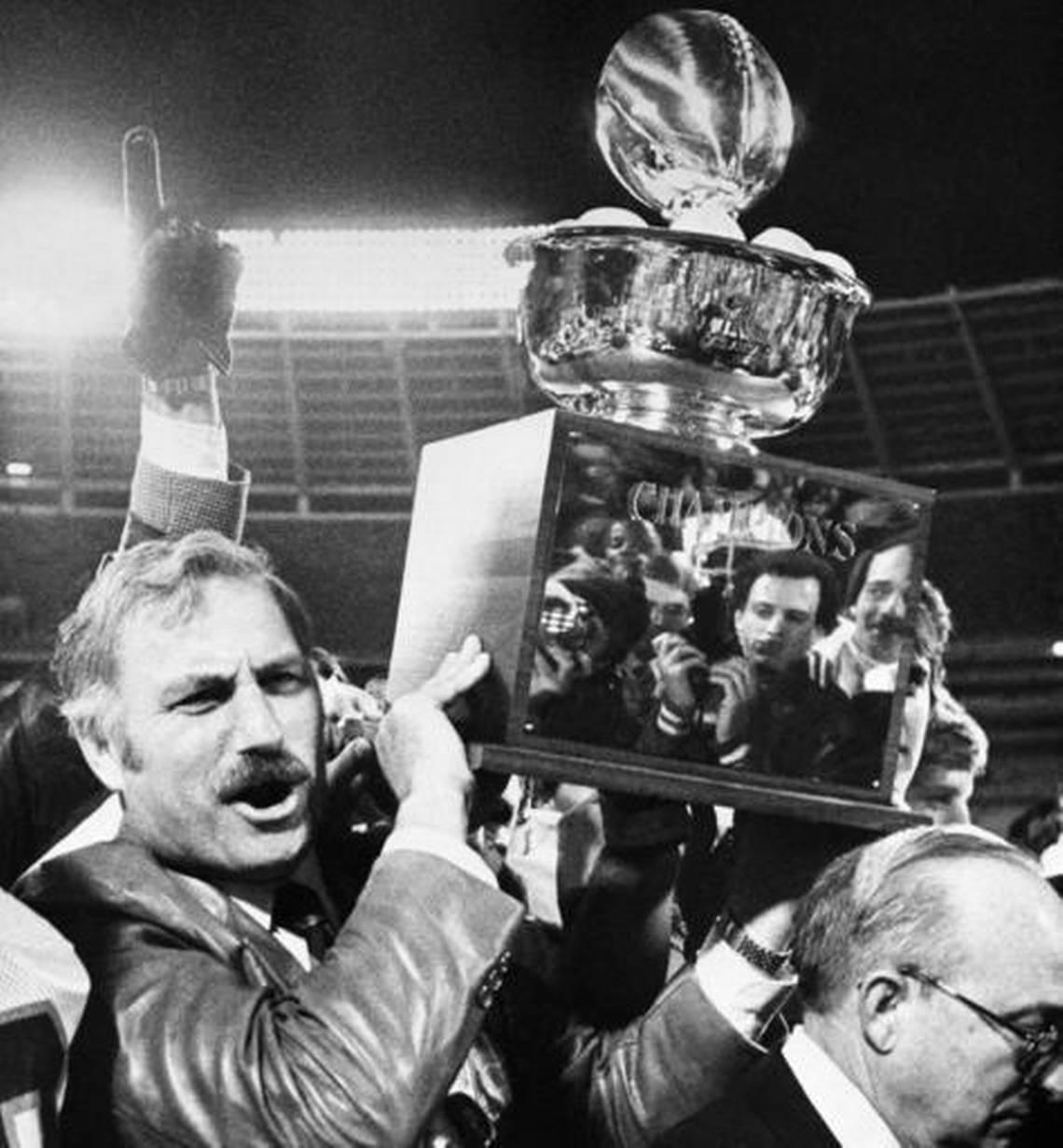 In this Jan. 2, 1981 file photo, University if Miami coach Howard Schnellenberger holds the 1981 Peach Bowl trophy aloft after his team defeated Virginia Tech, 20-10, in Atlanta. With three national titles in the 1980s _ all under different coaches, each of whom had a role in planting the seeds for what became five titles in a 19-season stretch _ the Hurricanes owned the decade.