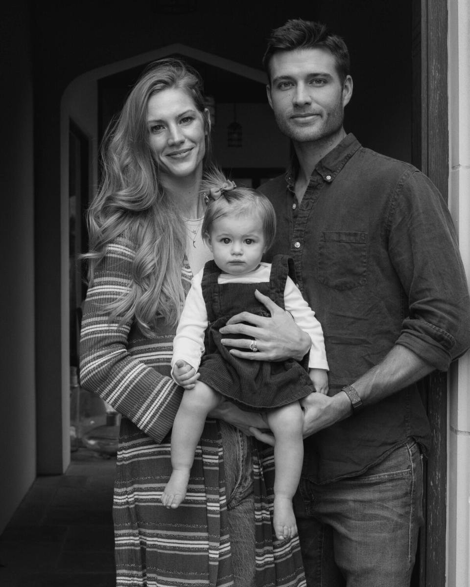 A couple holds their baby in an open doorway.