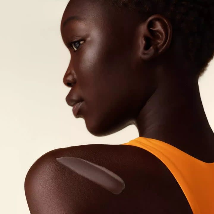 model with dark skin wearing the sunscreen on their skin