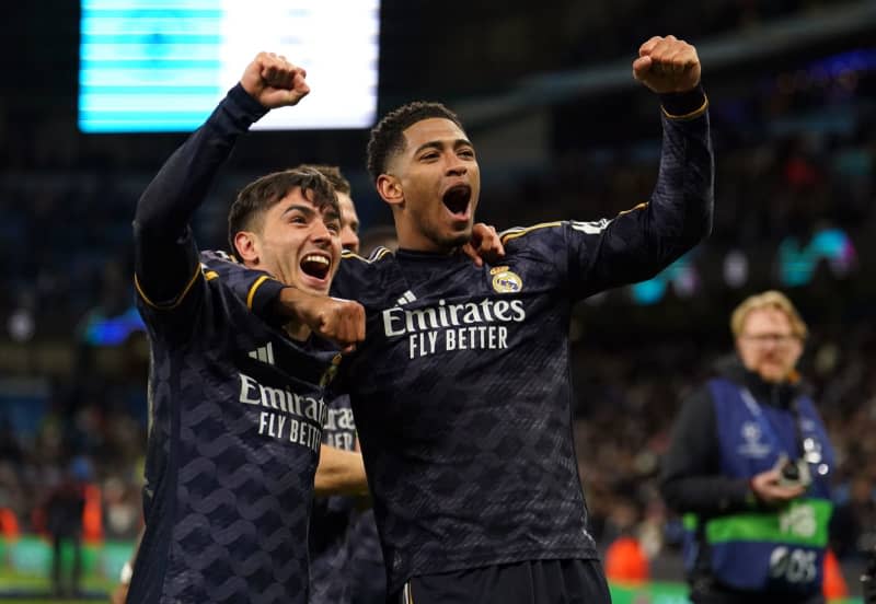 Real Madrid's Jude Bellingham (R) celebrates victory with teammate following the UEFA Champions League quarter-final second leg soccer match between Manchester City and Real Madrid at the Etihad Stadium, Manchester. Martin Rickett/PA Wire/dpa