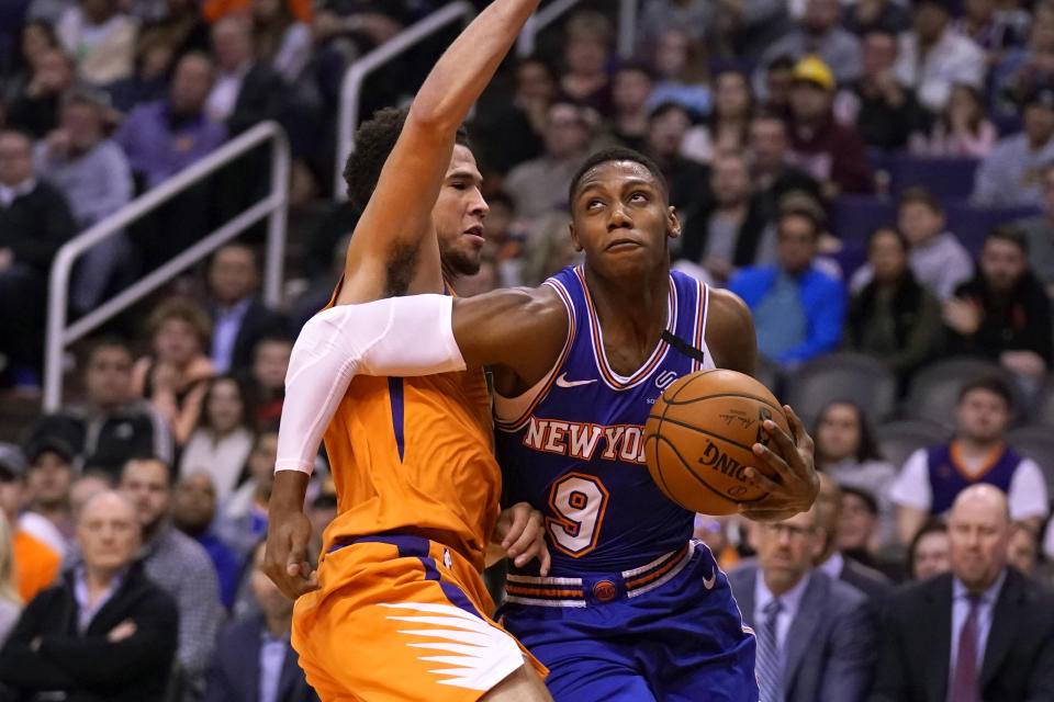 New York Knicks guard RJ Barrett (9) drives against Phoenix Suns guard Devin Booker in the first half of an NBA basketball game, Friday, Jan. 3, 2020, in Phoenix. (AP Photo/Rick Scuteri)