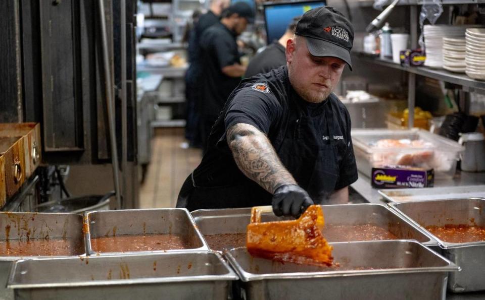 Logan Gaspard, a pitmaster at Jack Stack Barbecue’s Freight House location, divides beans into serving trays.