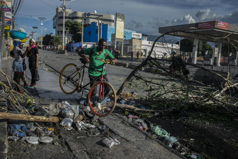 A man carries a bicycle while crossing a barricade in Port-au-Prince, Haiti, Wednesday, Oct. 12, 2022. (AP Photo/Odelyn Joseph)