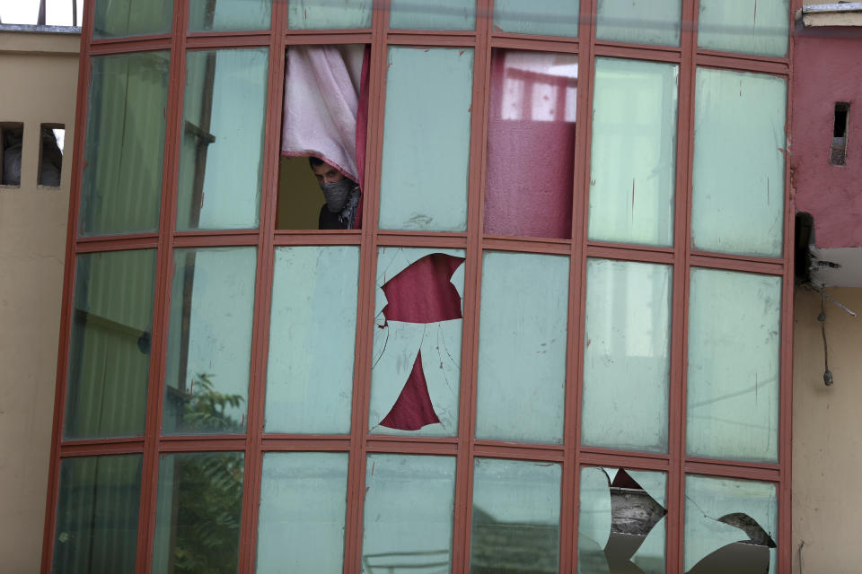 A man looks out from a broken window after a rocket attack in Kabul, Afghanistan, Tuesday, Aug. 18, 2020, Several mortar shells slammed into various part of Kabul on Tuesday morning as Afghans marked their country's Independence Day amid new uncertainties over the start of talks between the Taliban and the Kabul government. (AP Photo/Rahmat Gul)