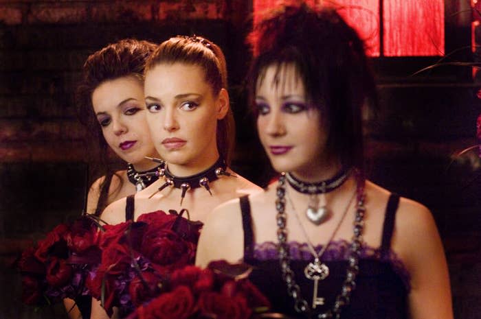 Three bridesmaids in gothic attire holding red roses with Katherine Heigl at the center in 27 Dresses