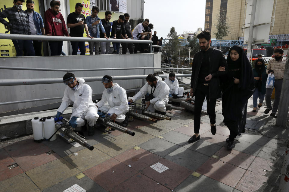 Firefighters prepare their fogging machines to disinfect a street against the new coronavirus as some people watch and pedestrians walk, in western Tehran, Iran, Friday, March 13, 2020. The new coronavirus outbreak has reached Iran's top officials, with its senior vice president, Cabinet ministers, members of parliament, Revolutionary Guard members and Health Ministry officials among those infected. The vast majority of people recover from the new coronavirus. According to the World Health Organization, most people recover in about two to six weeks, depending on the severity of the illness. (AP Photo/Vahid Salemi)