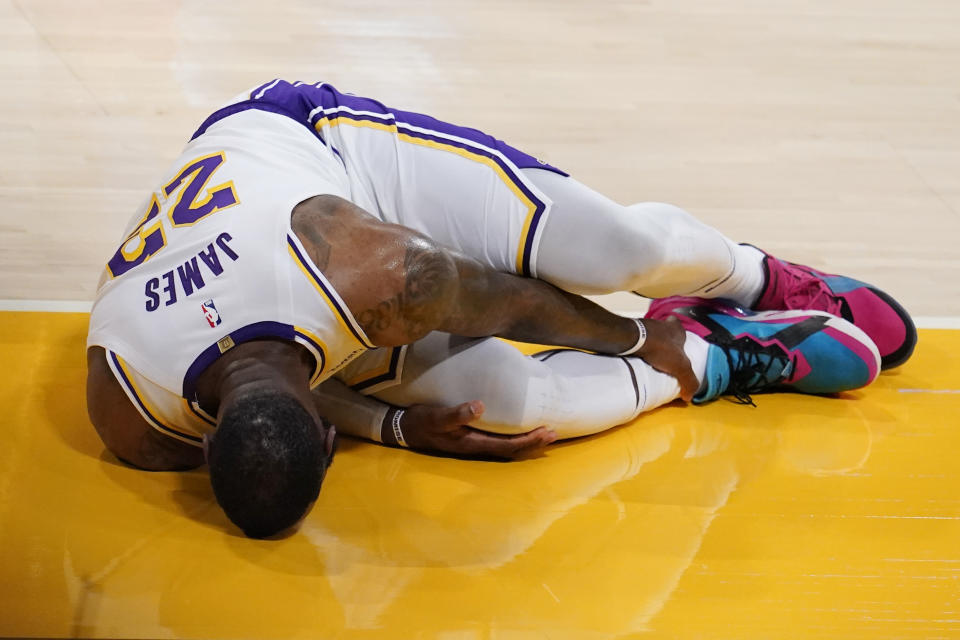 Los Angeles Lakers forward LeBron James holds his ankle after going down with an injury during the first half of an NBA basketball game against the Atlanta Hawks Saturday, March 20, 2021, in Los Angeles. (AP Photo/Marcio Jose Sanchez)