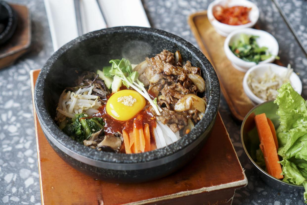 A bowl of rice topped with many vegetable, fried pork and egg yolk, a famous traditional Korean food called