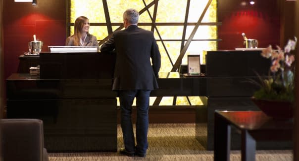 Businessmen speaking with staff at the front desk reception of a luxury hotel.