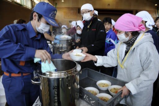 Tsurumaki town firefighters serve food to survivors at a makeshift shelter set up at a local junior high school in the city of Rikuzentakata in Iwate prefecture. Crews fighting to cool reactors at a stricken Japanese nuclear plant managed to connect a power line as the government revealed that leaking radioactivity had reached the food chain