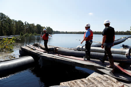 Santee Cooper workers check the water levels around a 6000 foot long Aqua Dam built to keep sediment from a coal ash retention pond from going into the flooded Waccamaw River in the aftermath of Hurricane Florence in Conway, South Carolina, U.S. September 26, 2018. REUTERS/Randall Hill