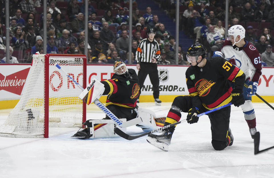 A shot by Colorado Avalanche's Nathan MacKinnon, not seen, goes over the net behind Vancouver Canucks goalie Collin Delia, left, as Canucks' Tyler Myers (57) and Avalanche's Artturi Lehkonen (62) watch during the second period of an NHL hockey game Friday, Jan. 20, 2023, in Vancouver, British Columbia. (Darryl Dyck/The Canadian Press via AP)