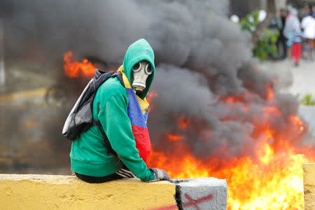 Demonstrator sits next to a fire barricade on a street during a rally against Venezuela's President Nicolas Maduro in Caracas, Venezuela April 24, 2017. REUTERS/Christian Veron