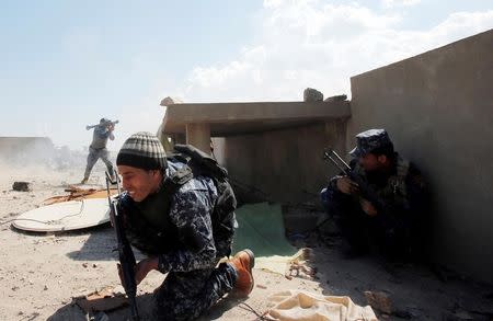 Iraqi federal policemen take cover as another fires a rocket at Islamic State fighters' positions at Bab al Jadid district in the old city of Mosul, Iraq, March 26, 2017. REUTERS/Youssef Boudlal