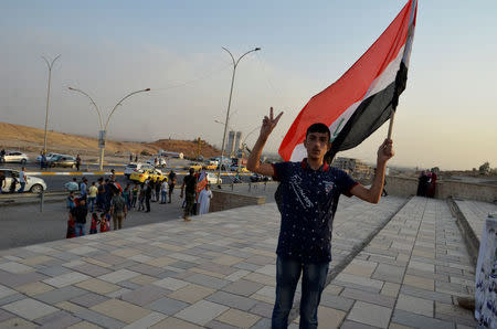 An Iraqi man carries an Iraqi flag as he celebrates the liberation of the embattled city of Mosul, in Mosul, Iraq July 9, 2017. REUTERS/Stringer NO RESALES. NO ARCHIVE